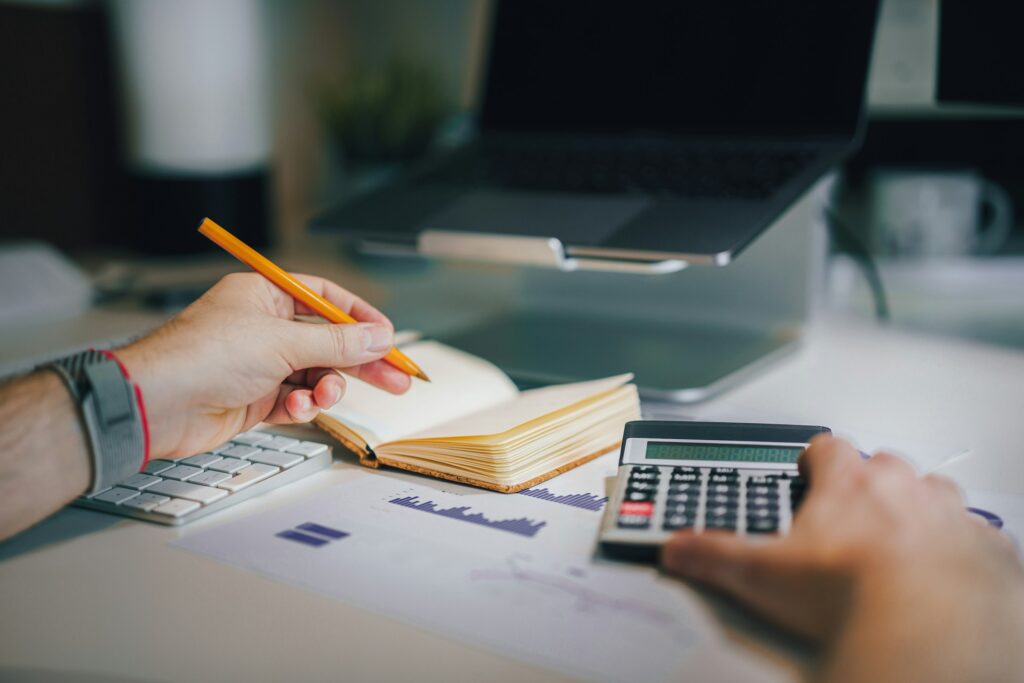 Personne utilisant un ordinateur, carnet, et calculatrice